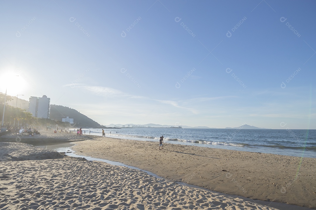 Praia com gente curtindo sol de fim de tarde e crianças brigando, conceito de turismo