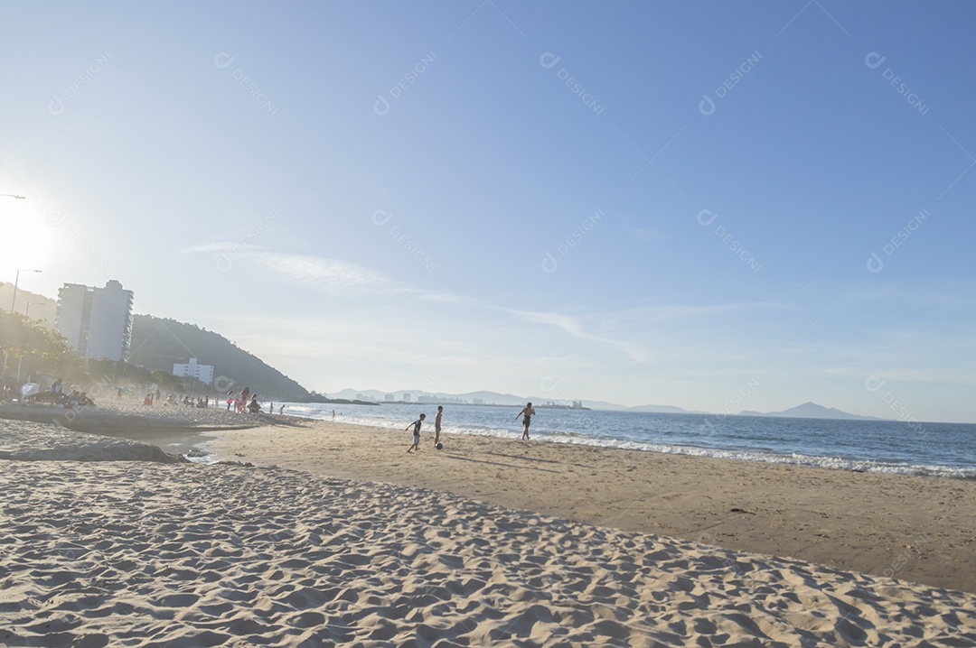 Praia com gente curtindo sol de fim de tarde e crianças brigando, conceito de turismo