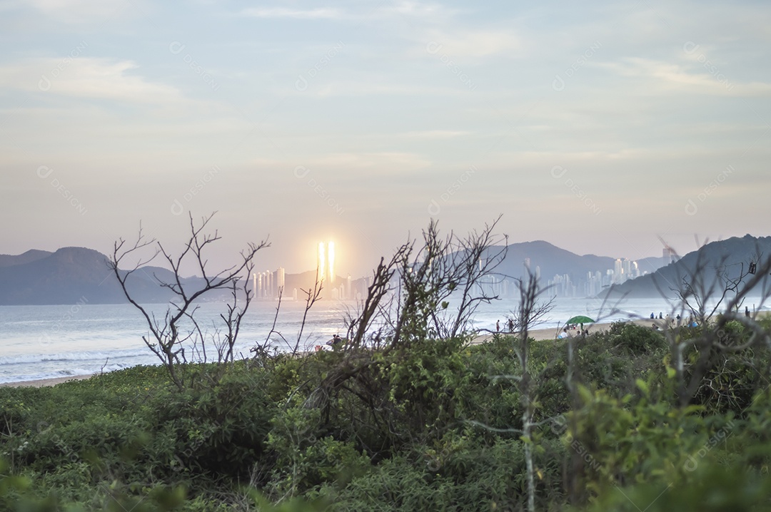 Praia brava em itajai-sc brasil com a cidade de balneário comboriu ao fundo e gente curtindo a praia conhecida por suas ondas altas.
