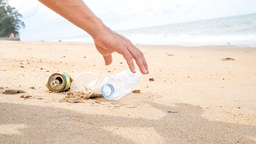 Mão pegando limpeza de garrafas plásticas na praia.