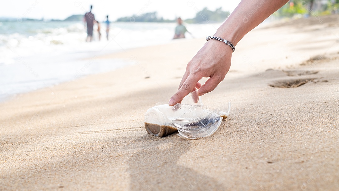 Mão pegando limpeza de garrafas plásticas na praia.