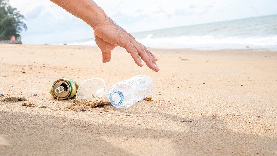Mão pegando limpeza de garrafas plásticas na praia.