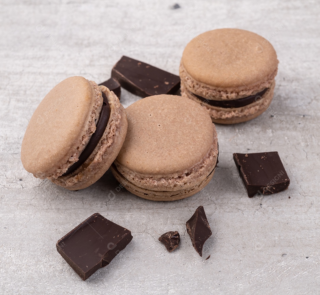 Macarons de chocolate escuro sobre fundo rústico.