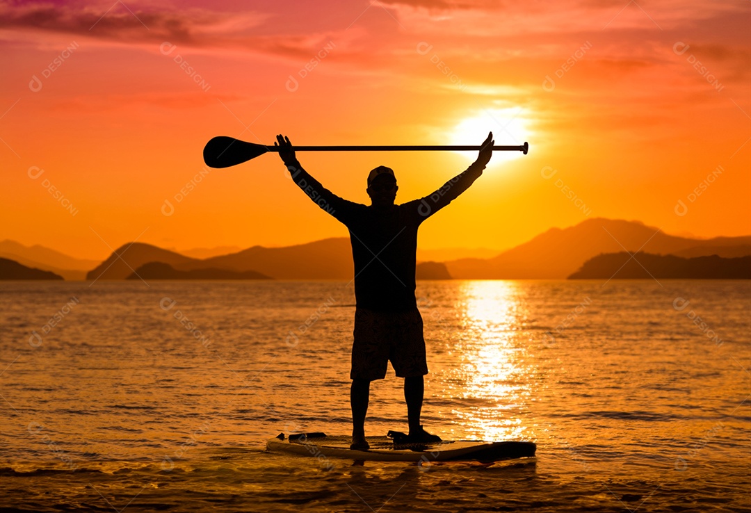 Silhueta de homem ao pôr do sol remando em seu caiaque na costa do Brasil