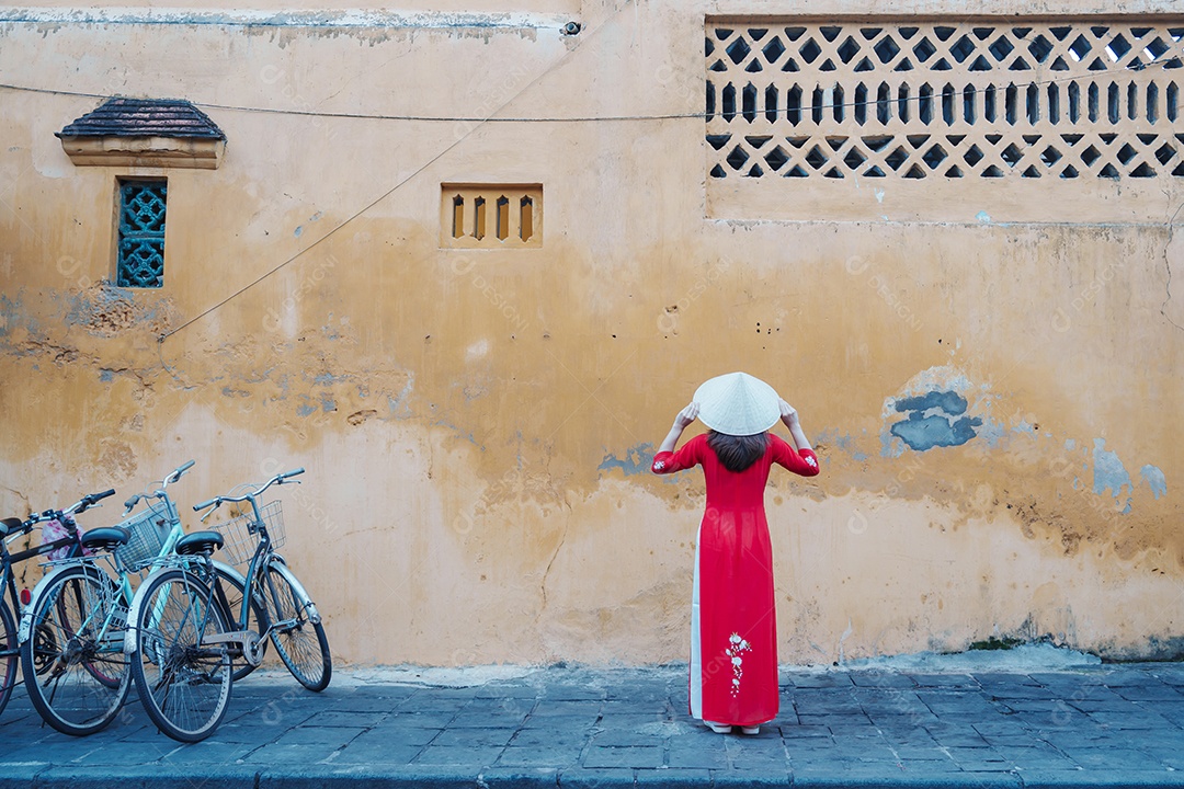 Mulher feliz usando vestido vietnamita Ao Dai, viajante asiático passeando em Hoi An, cidade antiga no centro do Vietnã.