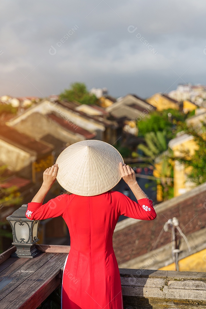 Mulher viajante usando vestido vietnamita Ao Dai passeando na ponte coberta japonesa na cidade de Hoi An, Vietnã.