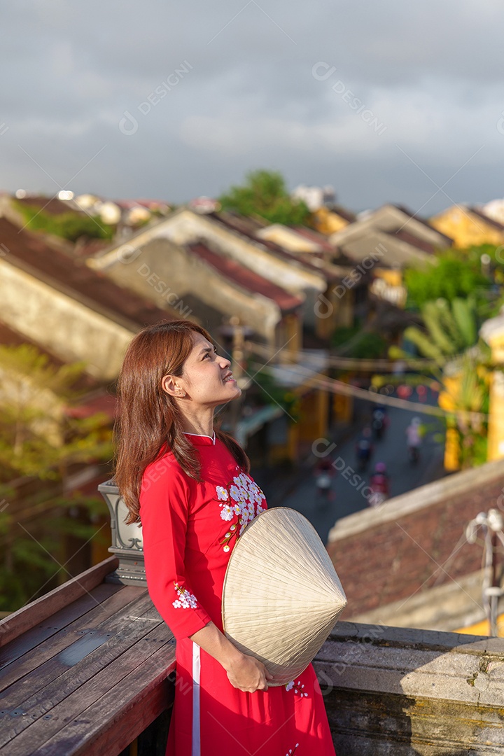 Mulher viajante usando vestido vietnamita Ao Dai passeando na ponte coberta japonesa na cidade de Hoi An, Vietnã.