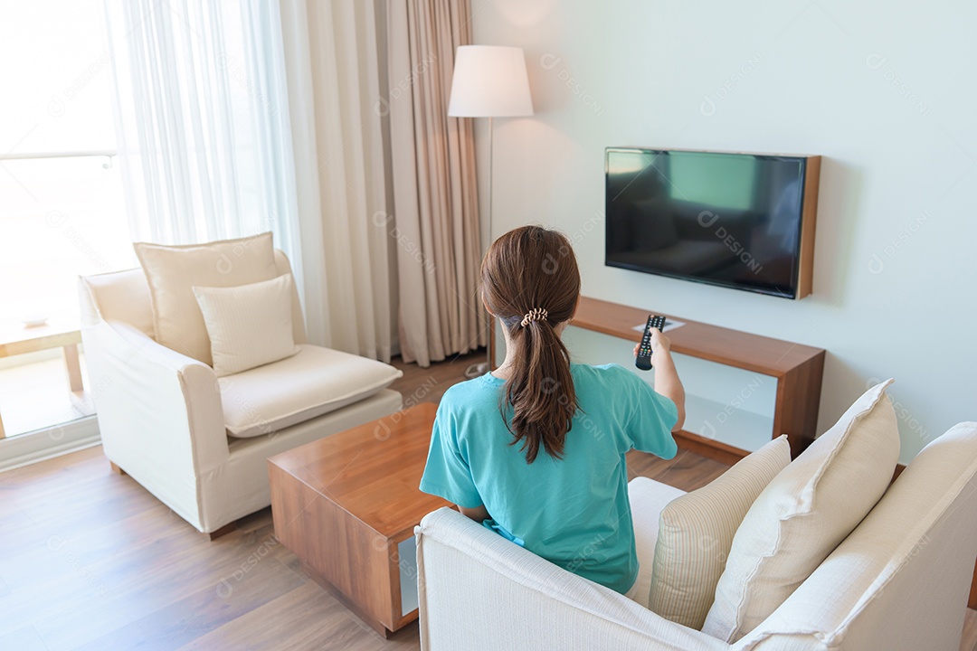 Mulher relaxando no sofá, Garota usando controle remoto e escolhendo programas de TV e séries de filmes durante o descanso no sofá pela manhã.