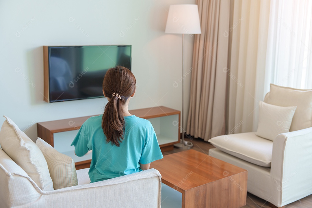Mulher relaxando no sofá, Garota usando controle remoto e escolhendo programas de TV e séries de filmes durante o descanso no sofá pela manhã.