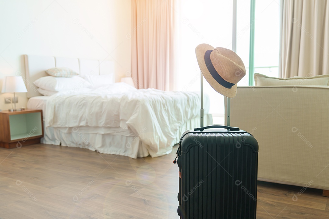 Bagagem preta com chapéu no quarto de hotel moderno após a abertura da porta.