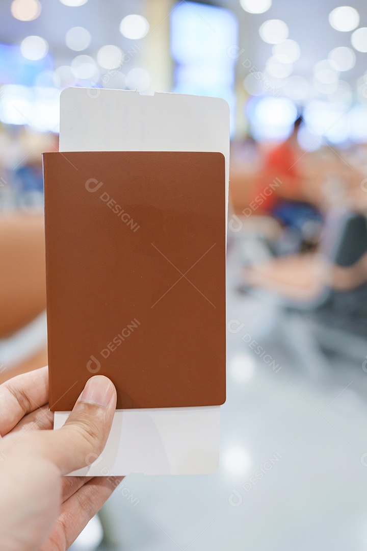 Mão segurando o passaporte da Tailândia e o bilhete de embarque no aeroporto internacional.