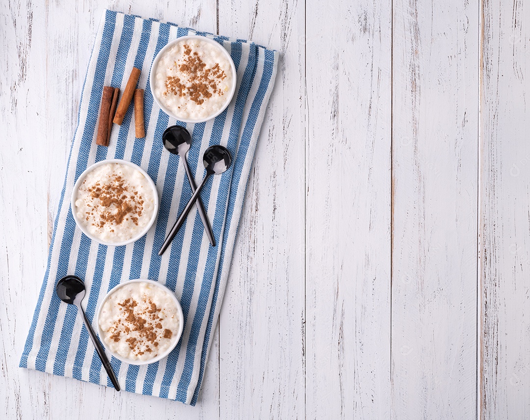 Canjica ou munguza, típico creme doce de milho branco brasileiro com canela sobre mesa de madeira com espaço para cópia.