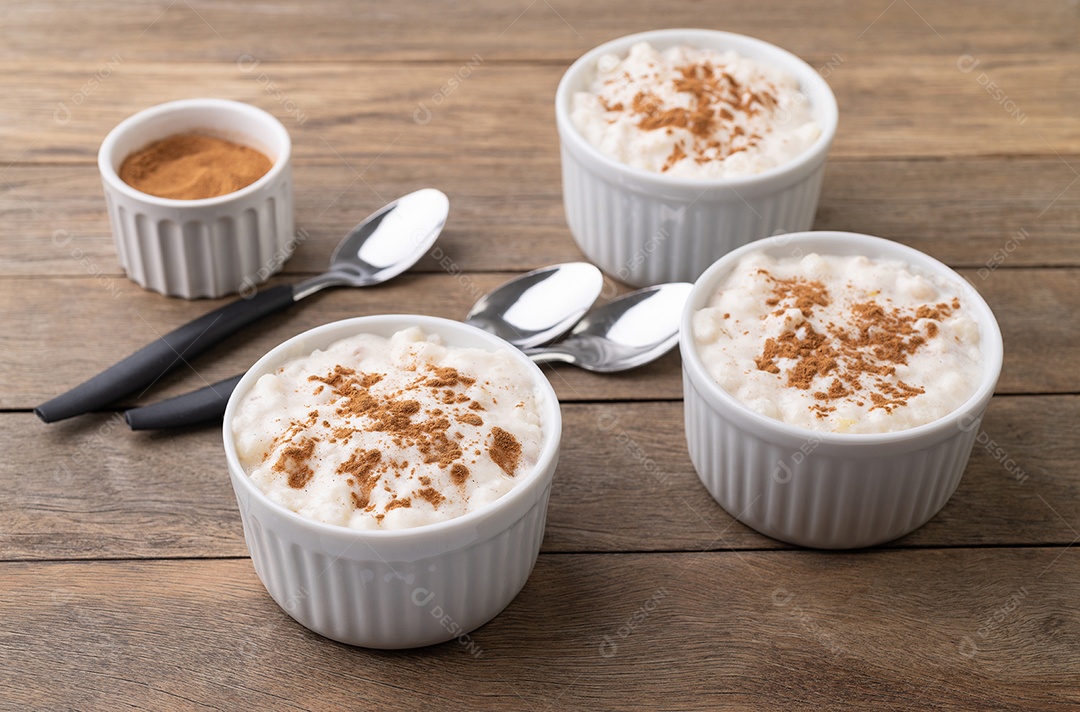 Canjica ou munguza, típico creme doce de milho branco brasileiro com canela sobre mesa de madeira.