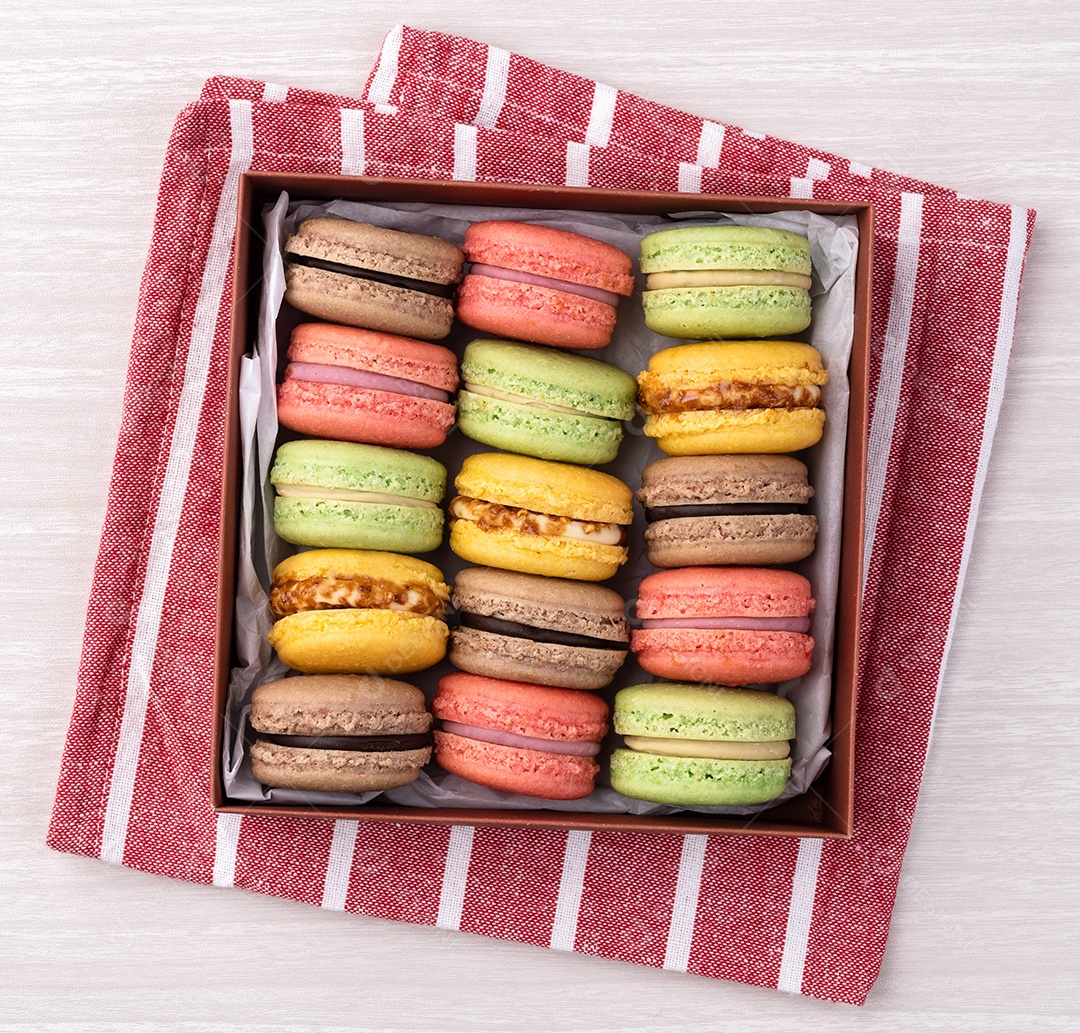 Macarons variados em uma caixa de presente sobre a mesa de madeira.