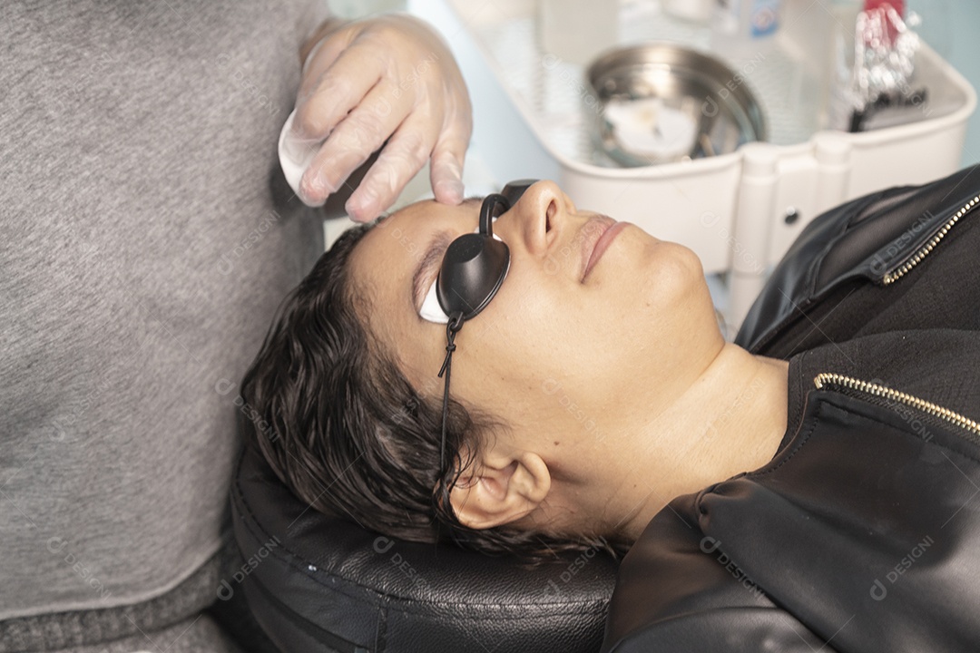 Mulher deitada, com espuma no rosto para despigmentar a sobrancelha