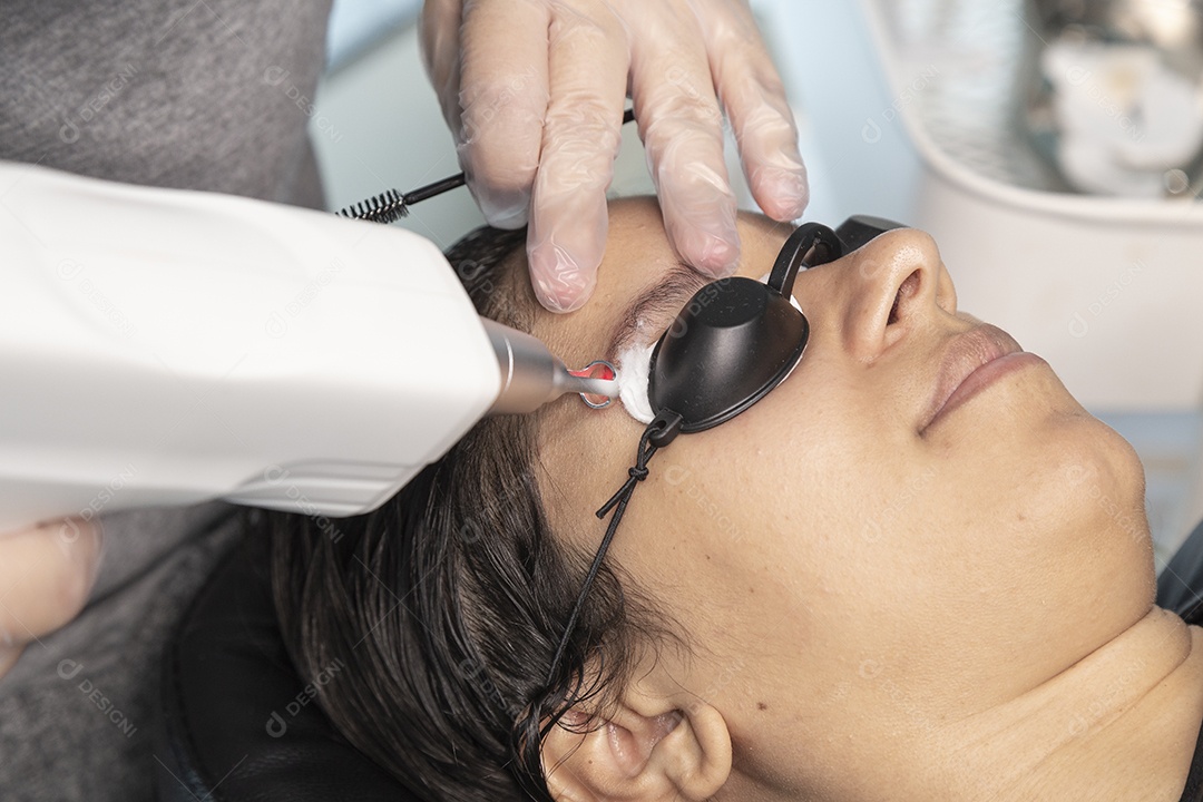 Mulher deitada, com espuma no rosto para despigmentar a sobrancelha