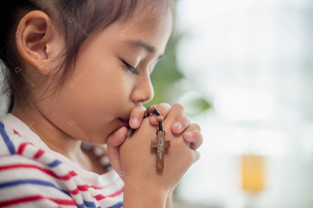 Conceito cristão. Menina asiática rezando retendo a cruz. Conceitos de esperança, fé, cristianismo, religião