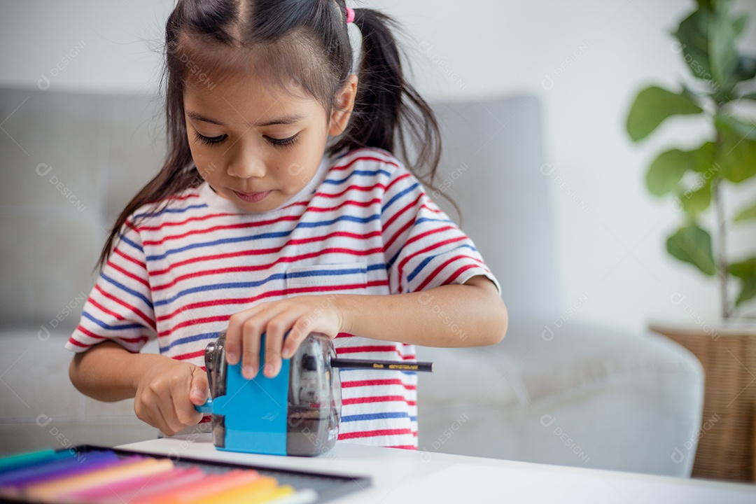 Aluna criança usando apontador de lápis ao fazer lição de casa. conceito de educação.