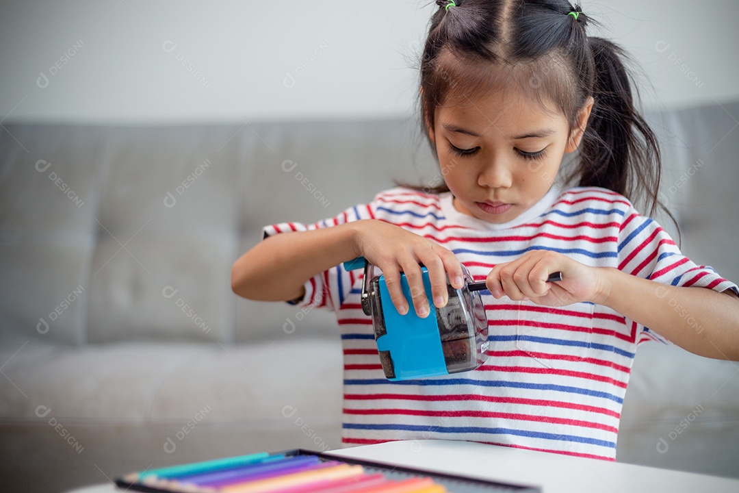 Aluna criança usando apontador de lápis ao fazer lição de casa. conceito de educação.