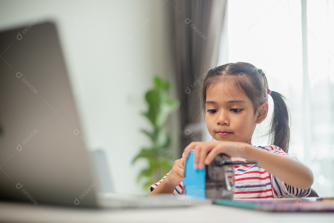 Aluna criança usando apontador de lápis ao fazer lição de casa. conceito de educação.