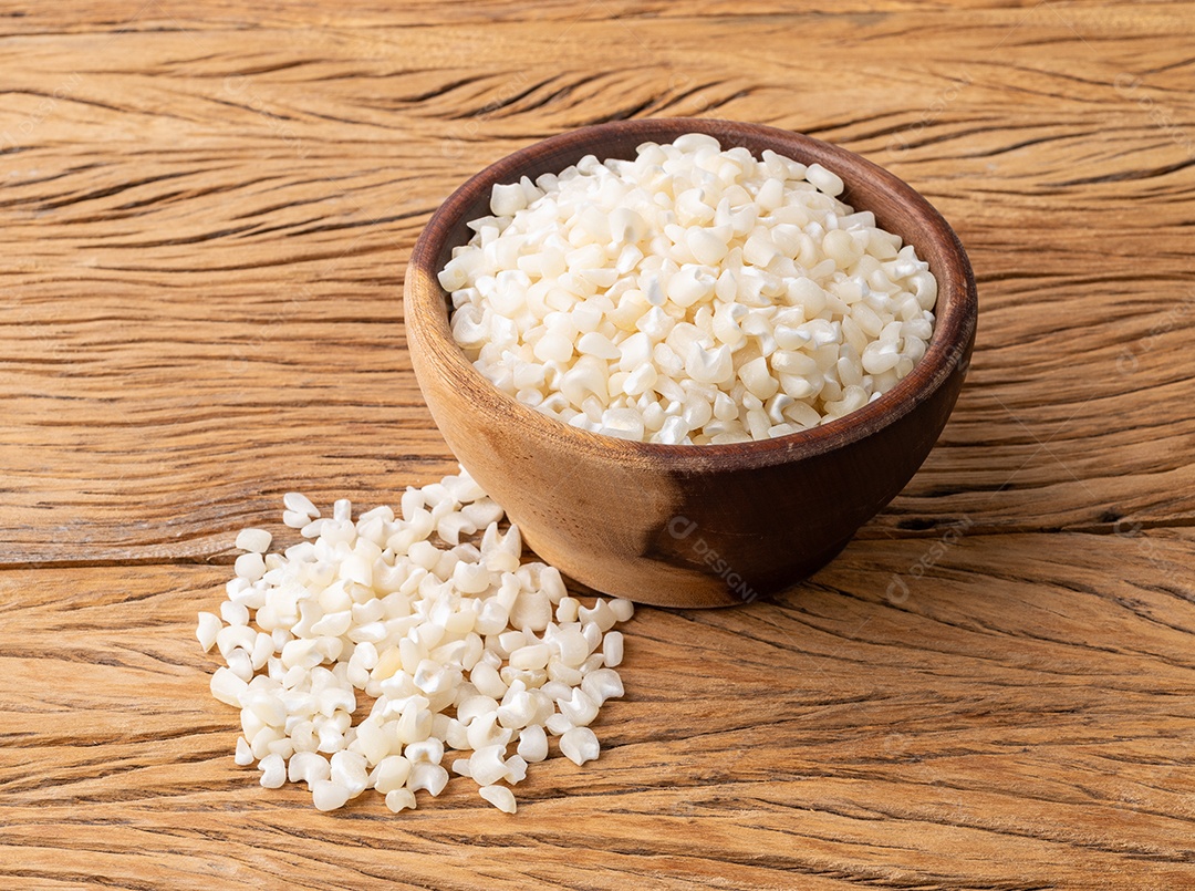 Canjica seca, canjica ou milho branco em uma tigela sobre a mesa de madeira.