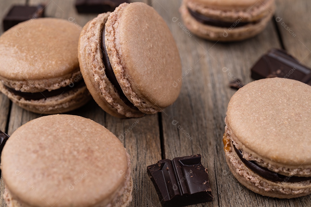 Macarons de chocolate escuro sobre fundo de madeira.