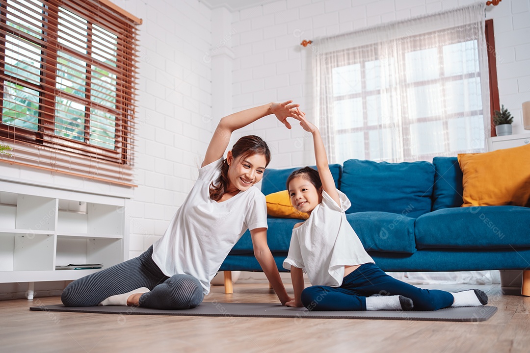 Mãe e filha se exercitando juntas e felizes em casa.