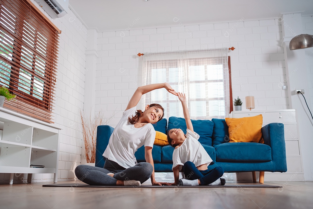 Mãe e filha se exercitando juntas e felizes em casa.