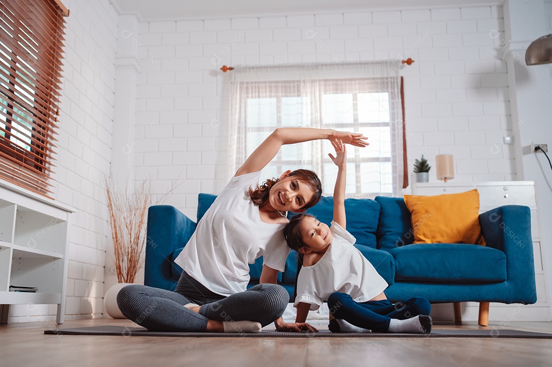 Mãe e filha se exercitando juntas e felizes em casa.