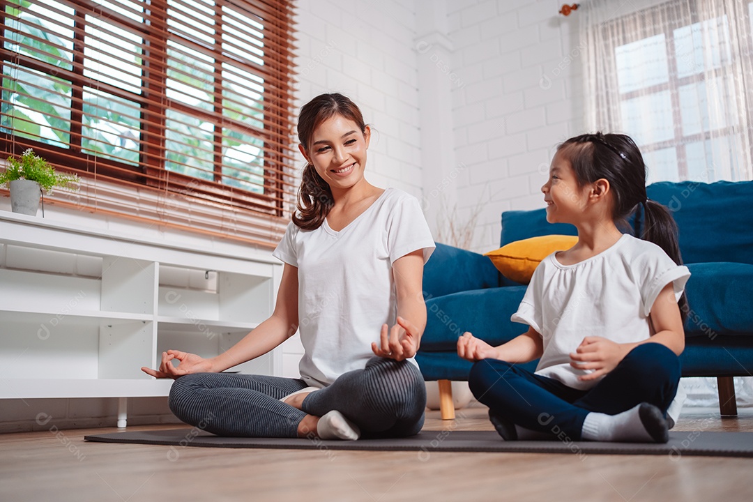 Mãe e filha se exercitando juntas e felizes em casa.