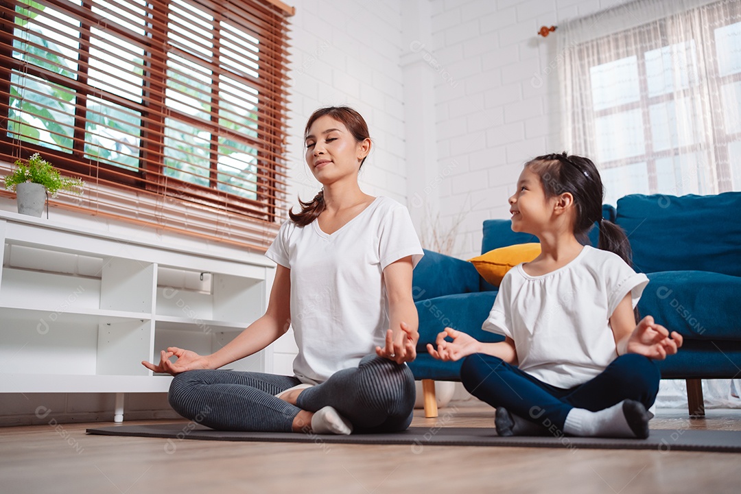 Mãe e filha se exercitando juntas e felizes em casa.