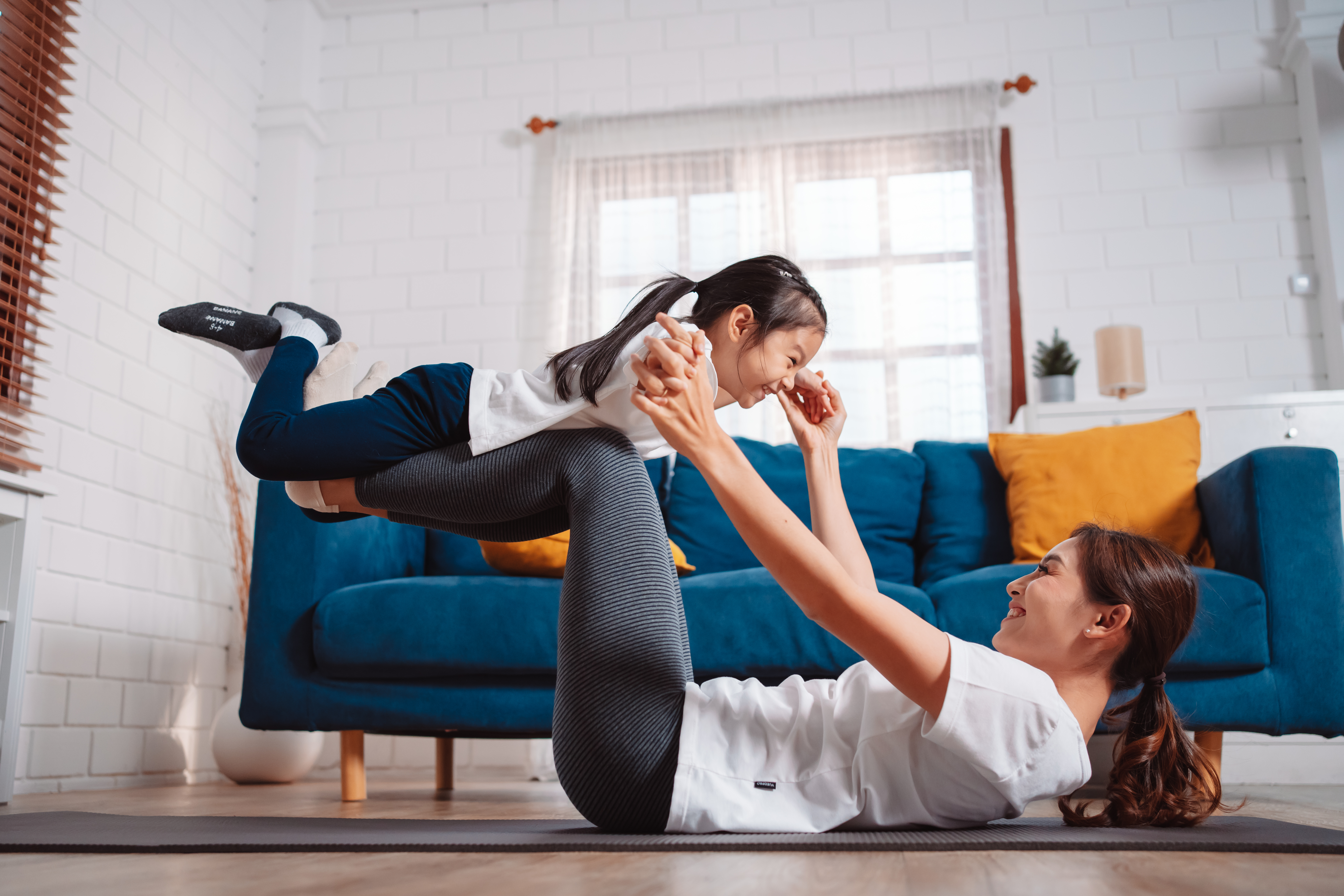 Mãe e filha se exercitando juntas e felizes em casa.
