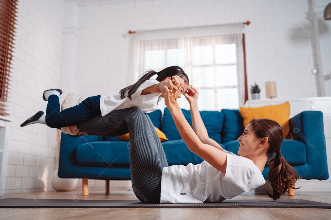 Mãe e filha se exercitando juntas e felizes em casa.