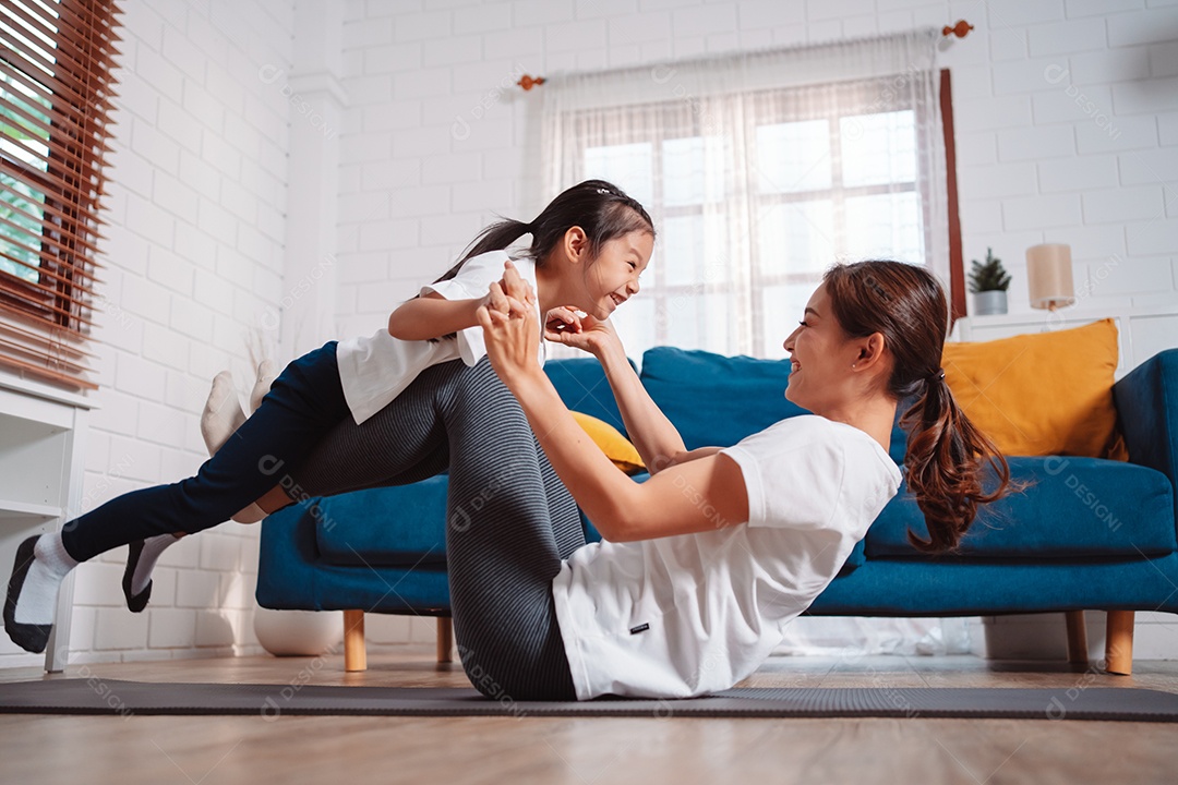 Mãe e filha se exercitando juntas e felizes em casa.