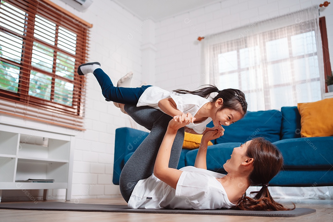 Mãe e filha se exercitando juntas e felizes em casa.