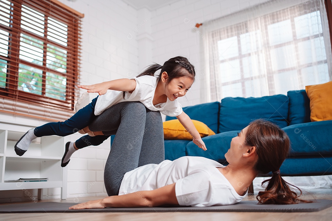 Mãe e filha se exercitando juntas e felizes em casa.