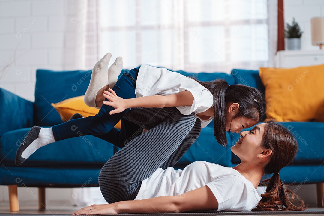 Mãe e filha se exercitando juntas e felizes em casa.