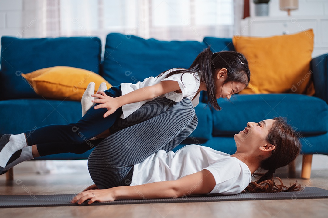 Mãe e filha se exercitando juntas e felizes em casa.