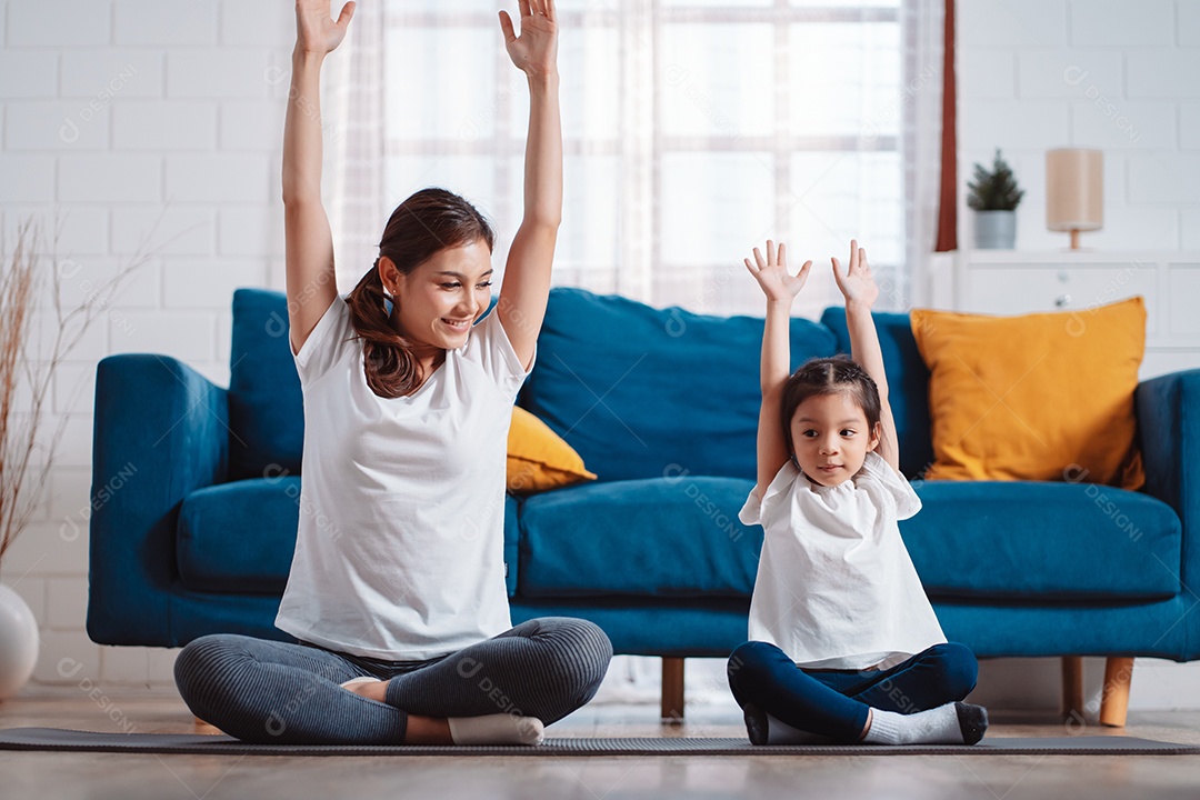 Mãe e filha se exercitando juntas e felizes em casa.