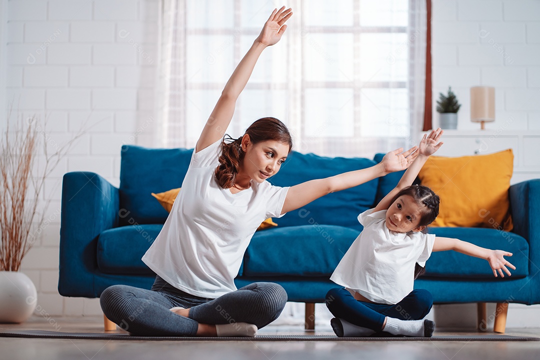 Mãe e filha se exercitando juntas e felizes em casa.