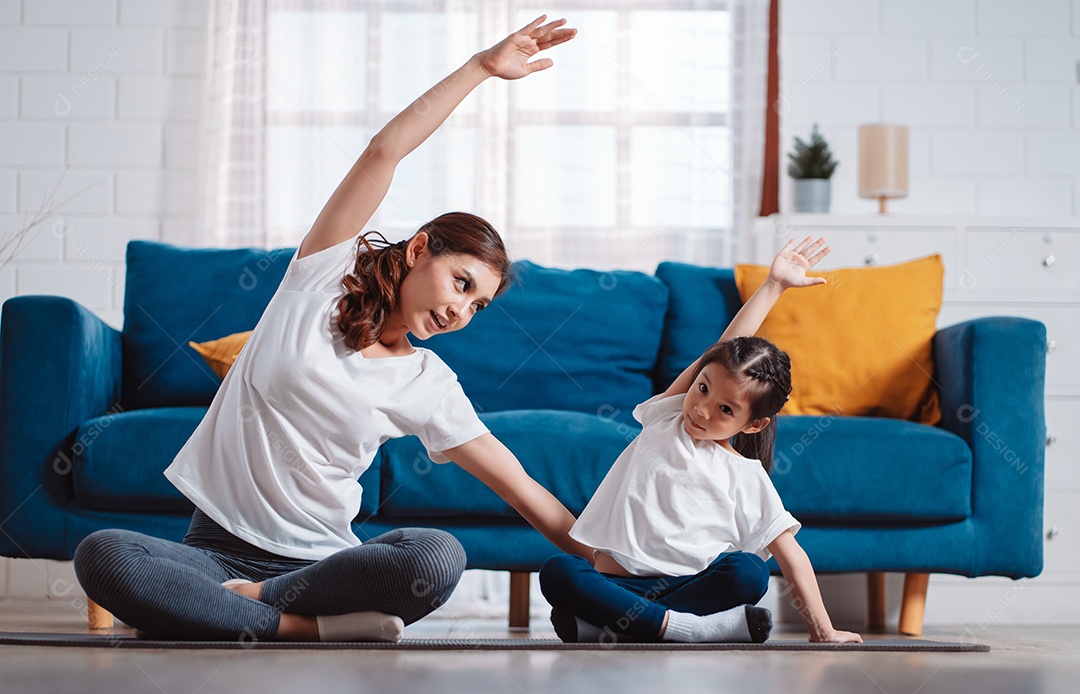 Mãe e filha se exercitando juntas e felizes em casa.