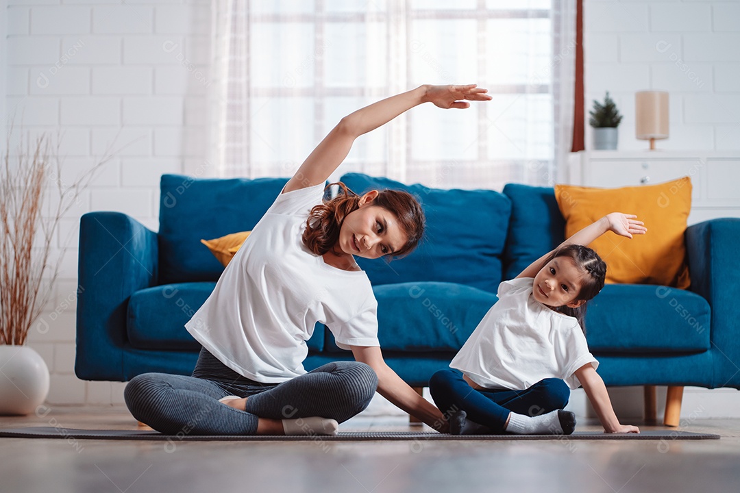 Mãe e filha se exercitando juntas e felizes em casa.