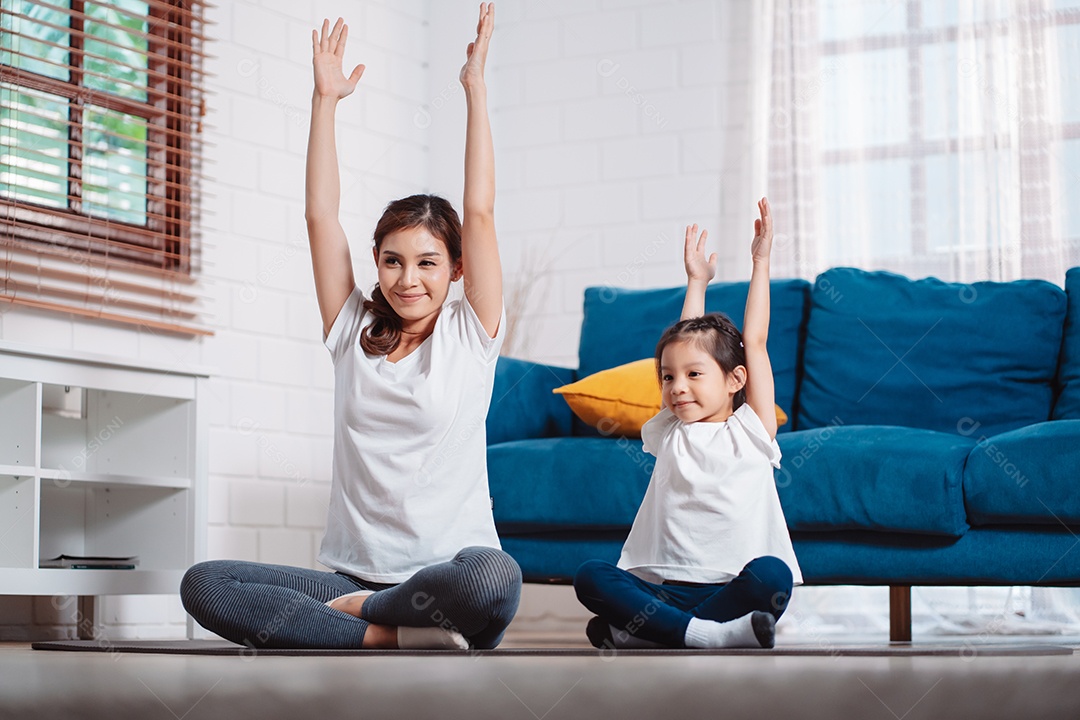 Mãe e filha se exercitando juntas e felizes em casa.