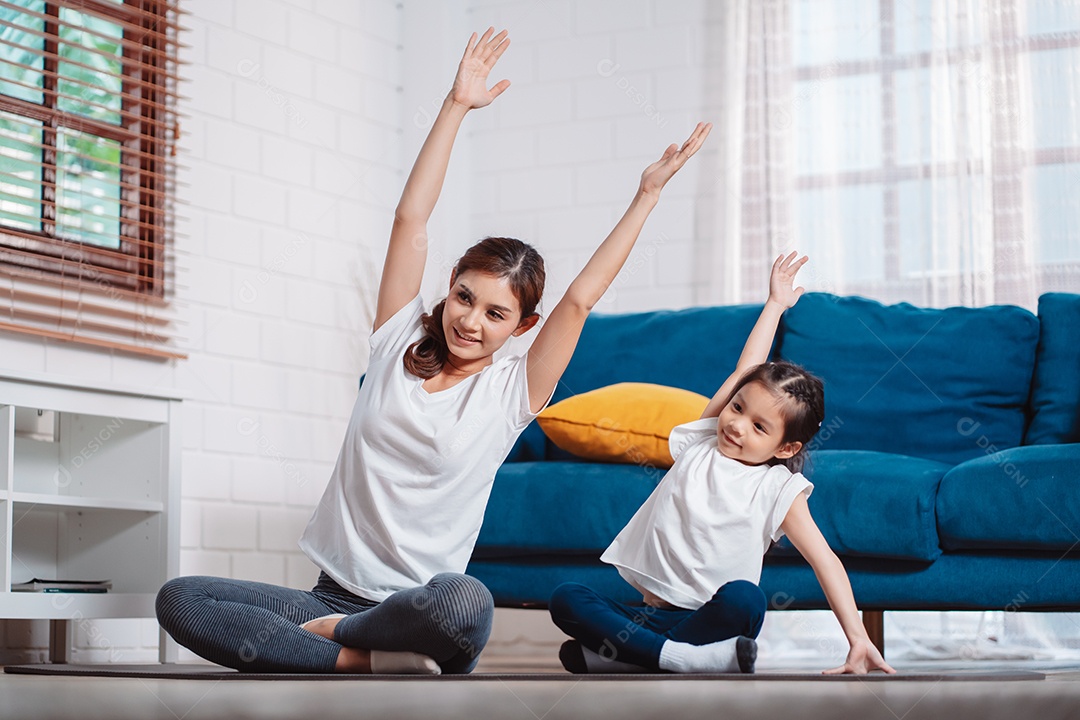 Mãe e filha se exercitando juntas e felizes em casa.