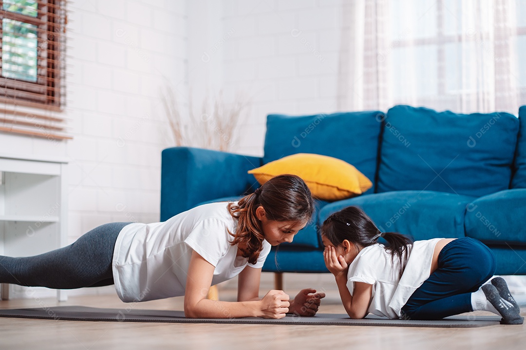 Mãe e filha se exercitando juntas e felizes em casa.