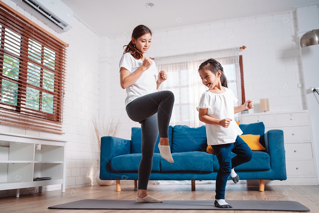 Mãe e filha se exercitando juntas e felizes em casa.