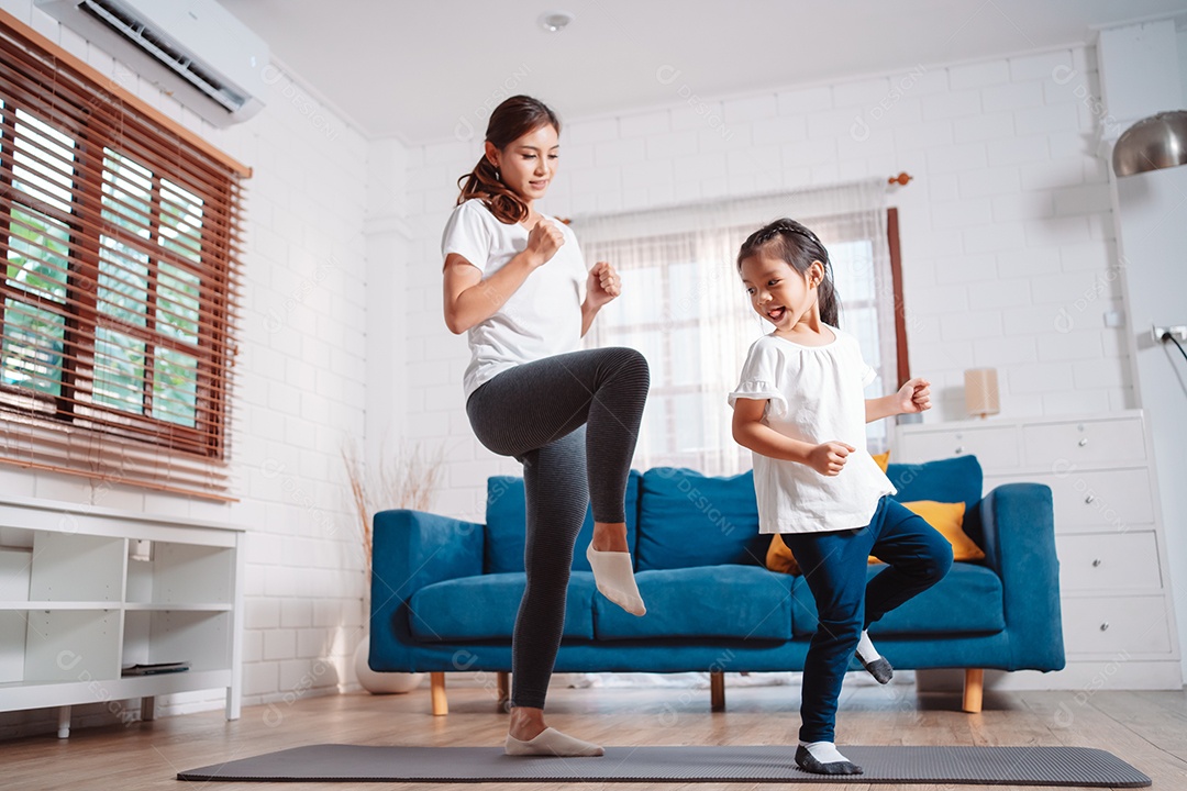 Mãe e filha se exercitando juntas e felizes em casa.