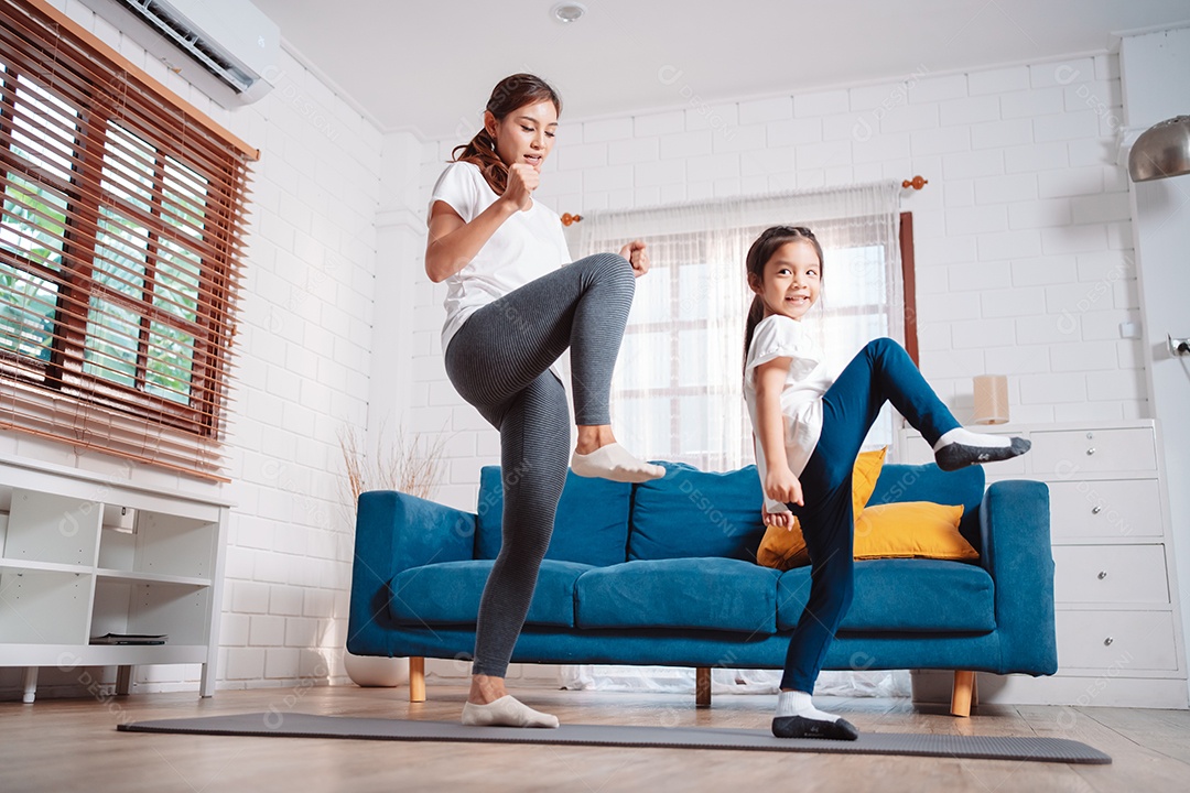 Mãe e filha se exercitando juntas e felizes em casa.