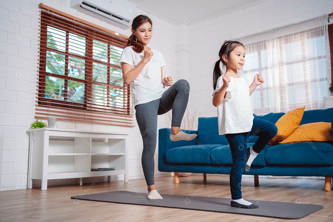 Mãe e filha se exercitando juntas e felizes em casa.