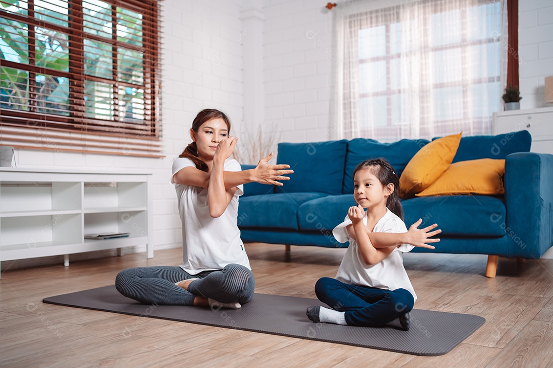 Mãe e filha se exercitando juntas e felizes em casa.